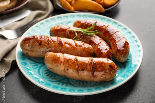 Plate with delicious grilled sausages on table