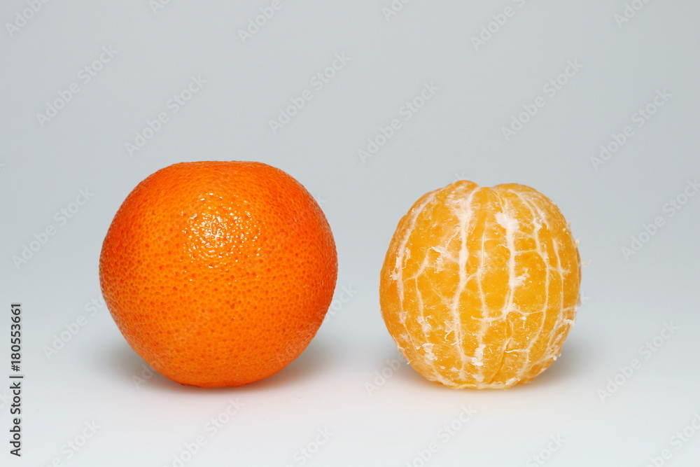 two tangerines on a white background: peeled and unpeeled two tangerines on a white background: peeled and unpeeled