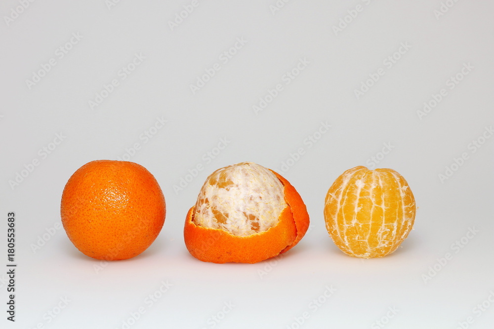 Three tangerines on a white background: uncleaned, peeled and in the middle of pelled