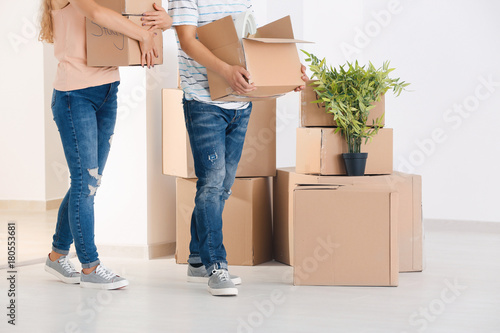 Young couple with moving boxes in room at new home