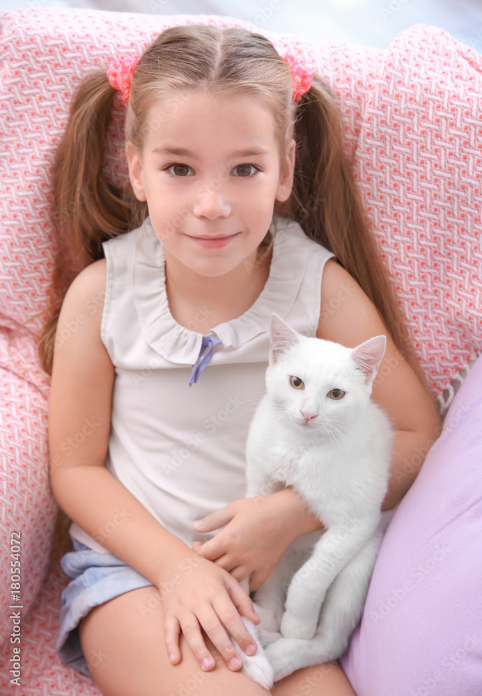 Little girl sitting in armchair with white cat indoors Little girl sitting in armchair with white cat indoors