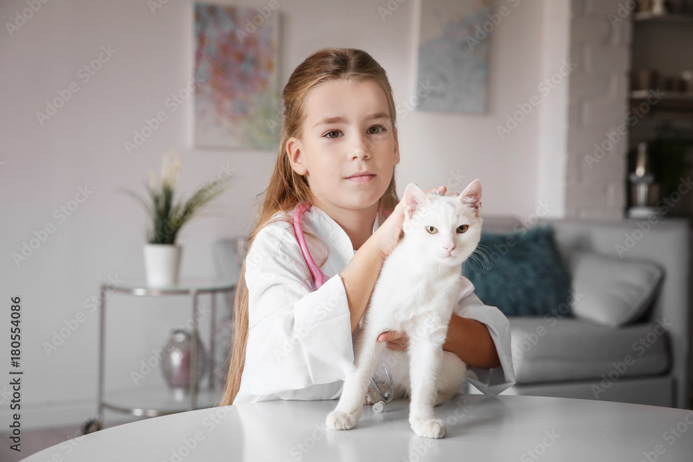 Little girl in doctor coat and white cat on table indoors Little girl in doctor coat and white cat on table indoors