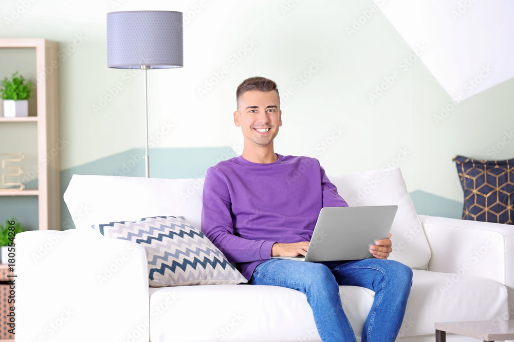 Young man using laptop on sofa at home Young man using laptop on sofa at home