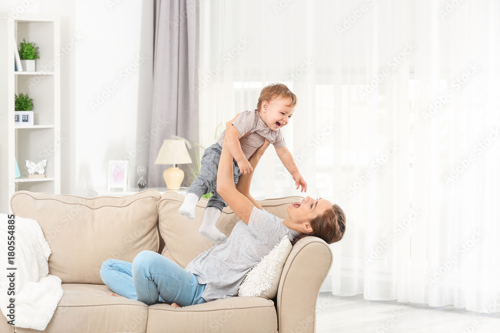 Mother with baby boy on sofa at home - obrazy, fototapety, plakaty 