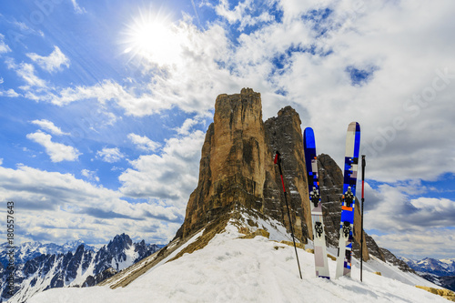 Mountaineer backcountry ski equipment in spring snow. In background blue cloudy sky and shiny sun and Tre Cime, Drei Zinnen in South Tirol, Dolomites, Italy. Adventure winter extreme sport.