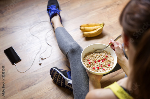 Plakat Young girl eating a oatmeal with berries after a workout . Fitness and healthy lifestyle concept.