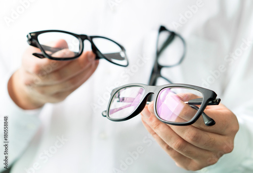 Foto Optician comparing lenses or showing customer different options in spectacles