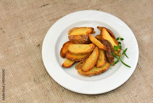 Fried potato wedges with herbs on plate.