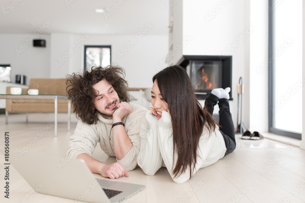 young multiethnic couple using a laptop on the floor young multiethnic couple using a laptop on the floor