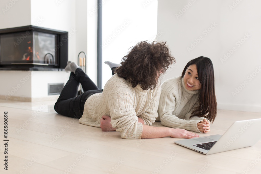 young multiethnic couple using a laptop on the floor young multiethnic couple using a laptop on the floor