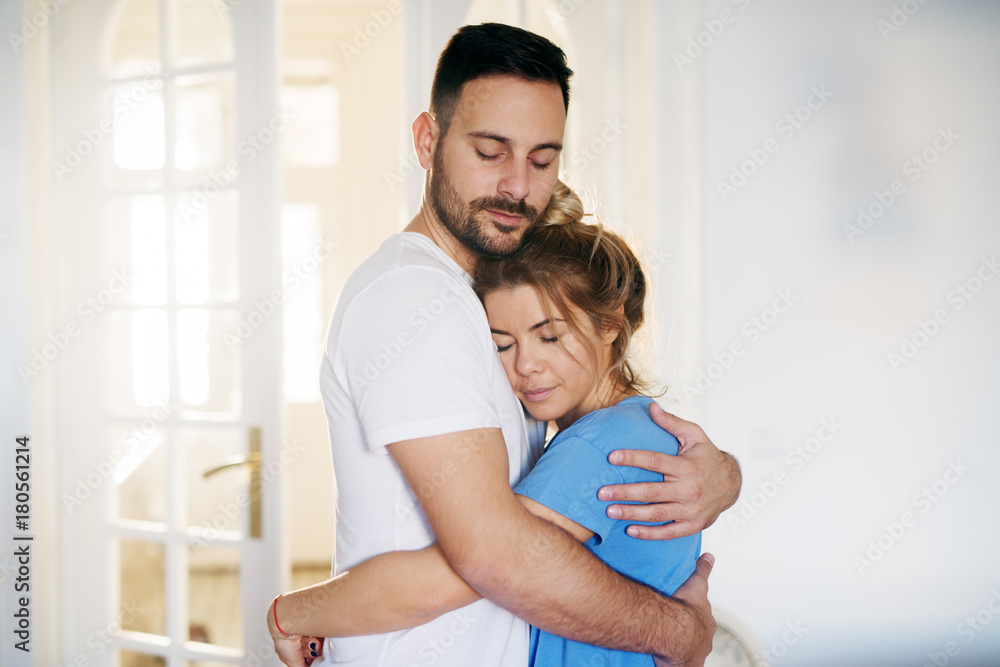 Romantic peaceful young love couple standing hugged with eye closed at home in pajamas. Romantic peaceful young love couple standing hugged with eye closed at home in pajamas.
