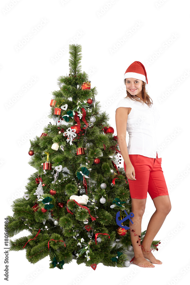 Beautiful woman with Santa hat standing near Christmas tree, isolated on white background