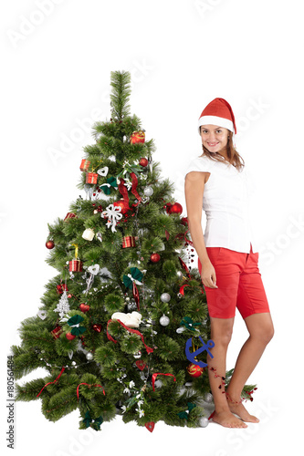 Beautiful woman with Santa hat standing near Christmas tree, isolated on white background