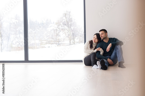 multiethnic couple sitting on the floor near window at home
