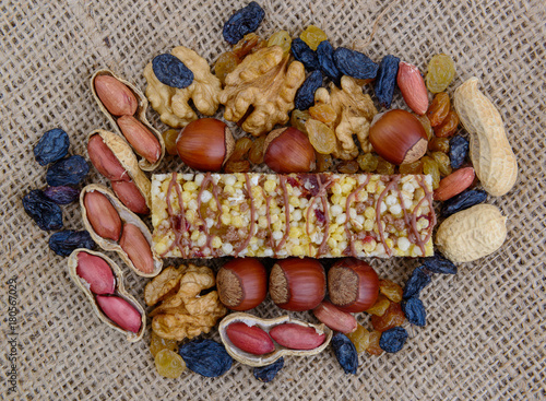 Granola (muesli, cereal) bar and its ingredients on canvas background.