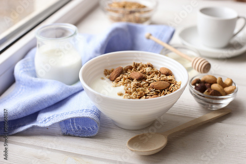 Healthy breakfast. Yogurt with granola and nuts on window sill