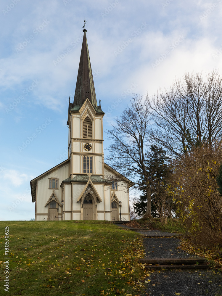 Lillesand, Norway - November 10, 2017: The church in Lillesand. Front view. Blue sky, clouds, green grass and stair.