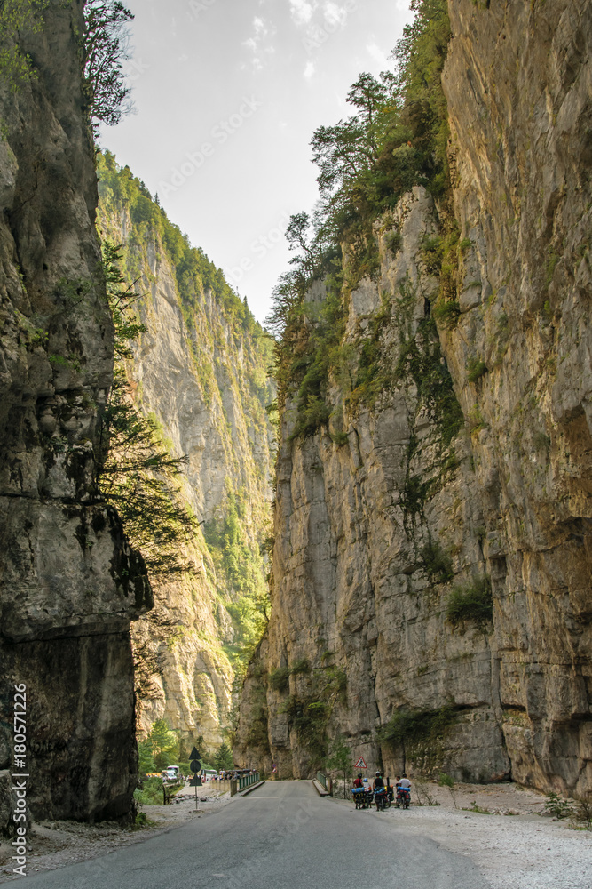 Bicyclists on asphalt road through gorge along Bzyb river near Ritsa lake in Abkhazia