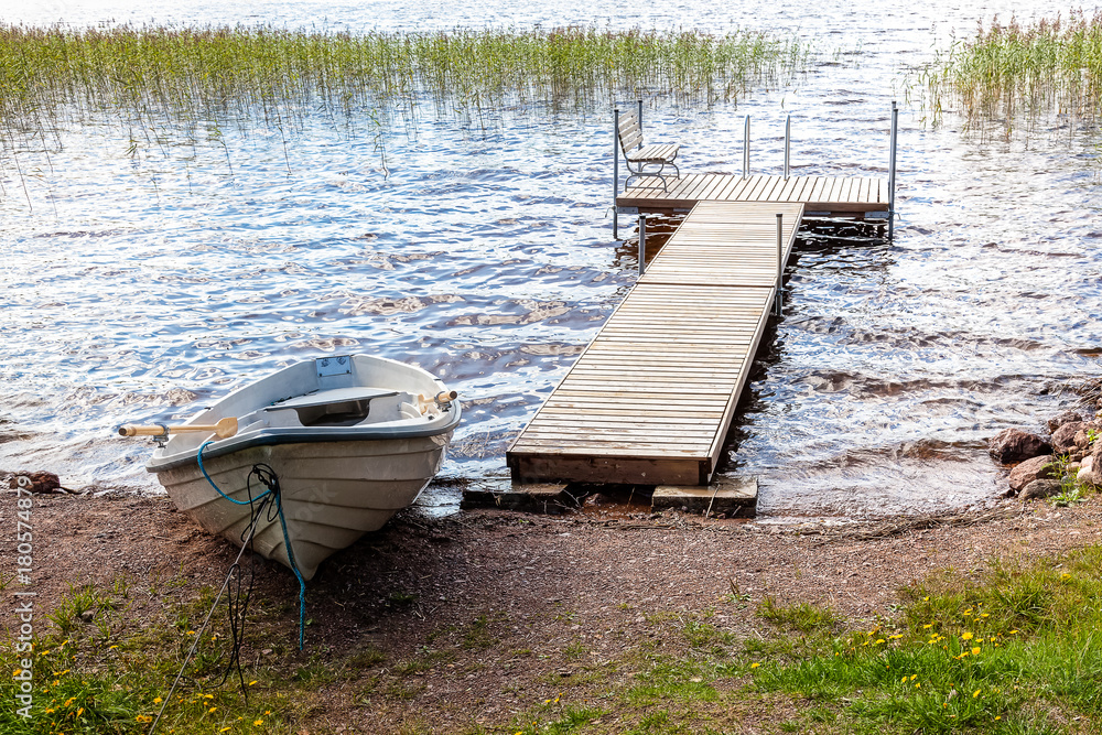 Jetty and boat are on lake in summer day