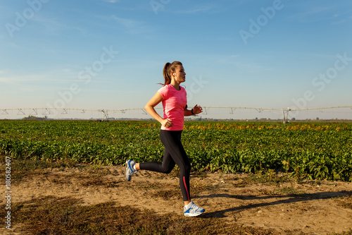 Athletic woman running on rural road.