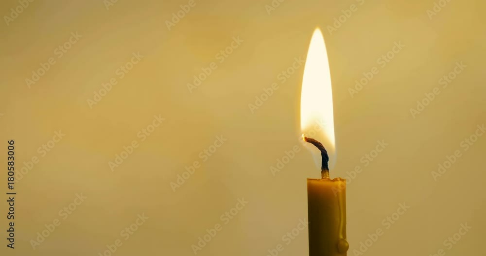Close-up of a wax candle burns on a yellow background. 4K. Close-up of a wax candle burns on a yellow background. 4K.