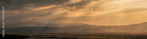 Amazing panorama with sun rays crossing from the clouds in this opening with a industrial city behind