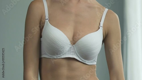 Fit female lifting breasts up with hands in front of mirror, small size, upset