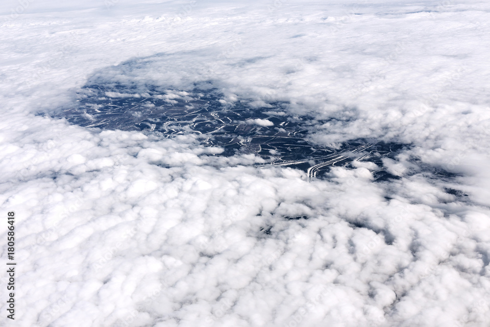 A view from the airplane window to clouds and earth.