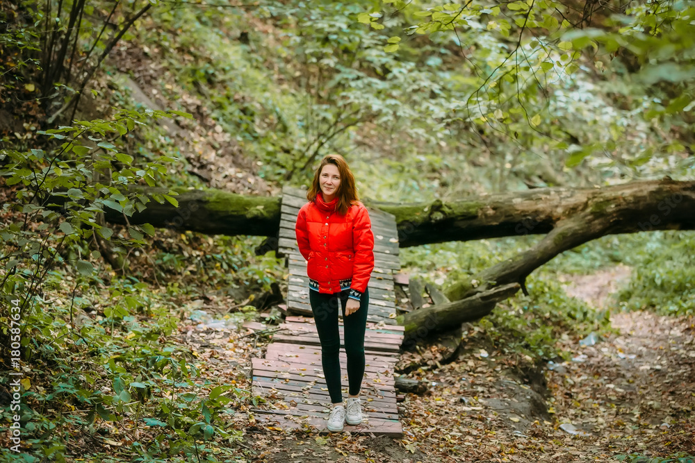 Cute sporty girl in red jacket is walking in forest. Autumn. Artwork