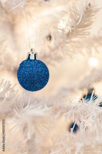 Blue glitter ball on white christmas tree, selective focus