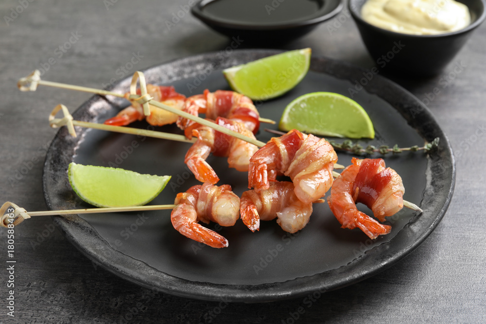 Plate with bacon-wrapped shrimps on table