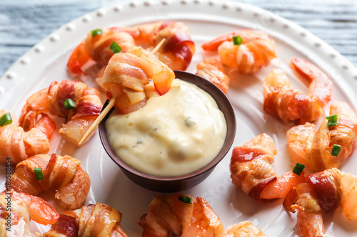 Obraz na plátně Plate with bacon-wrapped shrimps and tasty sauce, closeup
