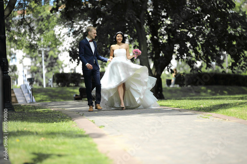 day of the wedding the beautiful bride and groom walk through the park © yurolaitsalbert