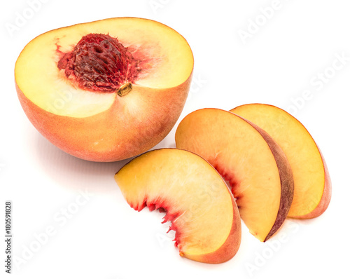 One peach half with a stone and three slices near isolated on white background.