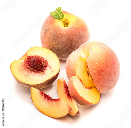 Peaches, one whole, one half and cut open, three slices, isolated on white background.