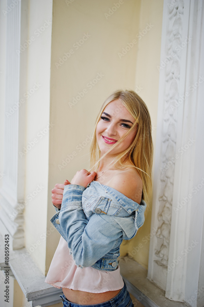 Blonde girl wear on jeans posed against old house. Blonde girl wear on jeans posed against old house.