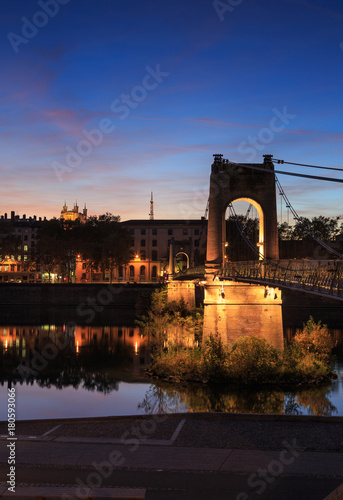 Illuminated footbridge Passerelle du College over the Rhone river in Lyon during dusk.