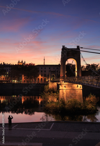 Photographing illuminated footbridge Passerelle du College over the Rhone river in Lyon at dusk.