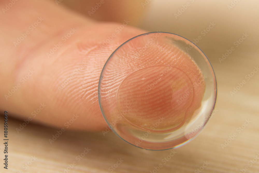 Contact lenses for eyes on a human finger on a wooden table Contact lenses for eyes on a human finger on a wooden table