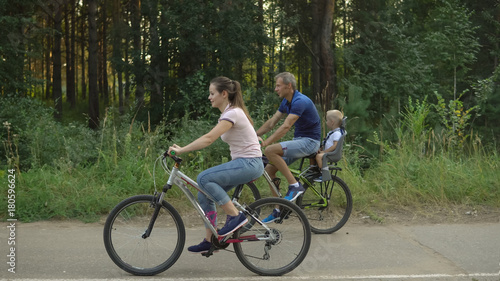 Happy family rides on bicycles in the forest