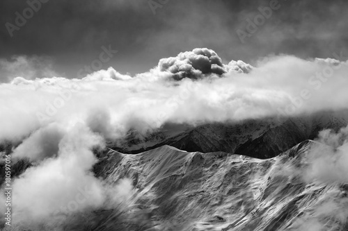 Black and white view on slope for freeriding at mist and sunlight clouds