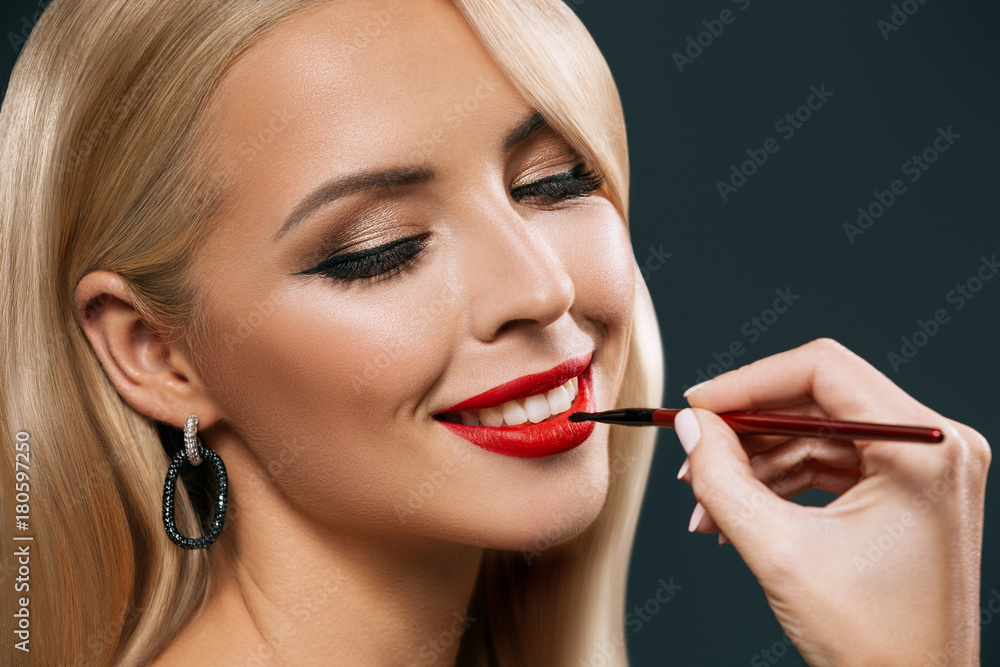 smiling woman applying red lipstick smiling woman applying red lipstick