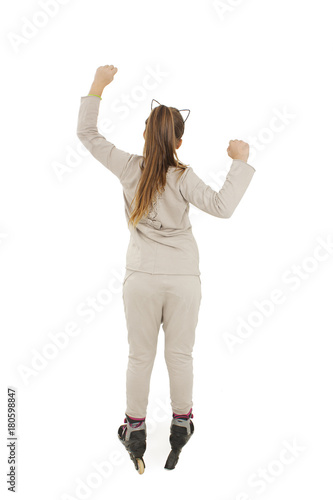 Back view of young girl arms up happy on rollers looking at wall. Rear view. Isolated on white background