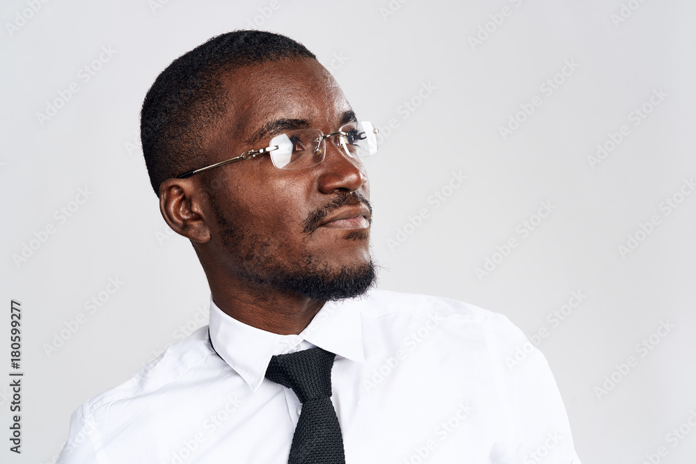 African man in a white shirt and glasses looks toward a close-up African man in a white shirt and glasses looks toward a close-up