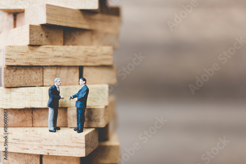 Miniature people: Businessman standing on wood block © Sirichai Puangsuwan