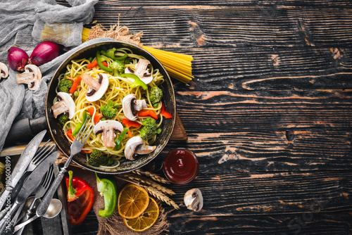 Noodles with vegetables in a frying pan. Asian Cuisine Pasta. Top view. Free space. On a wooden background.;