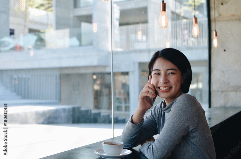 Beautiful Asian woman drinking coffee in coffee shop .