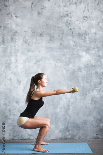Beautiful fitness girl with dumbbells on a gray background.