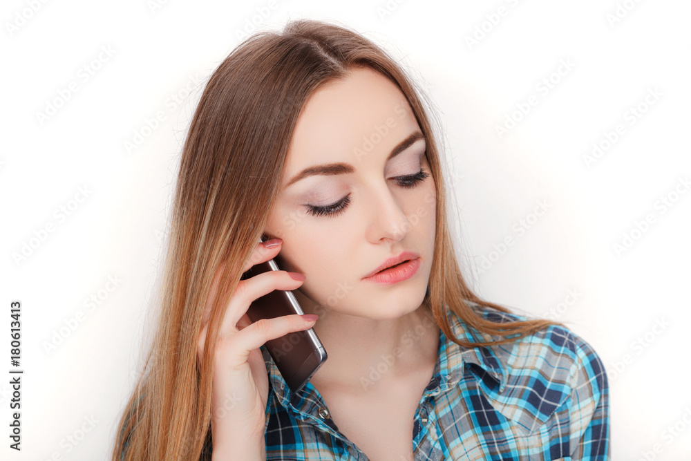 Portrait of a young adorable blonde woman in blue plaid shirt enjoying having emotional conversation on smartphone. Portrait of a young adorable blonde woman in blue plaid shirt enjoying having emotional conversation on smartphone.