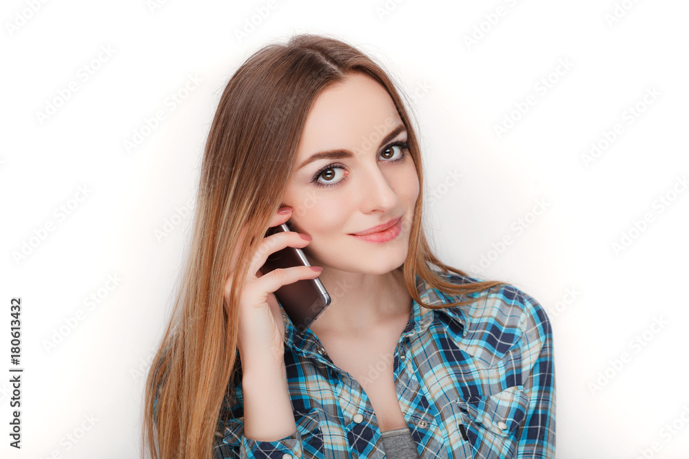 Portrait of a young adorable blonde woman in blue plaid shirt enjoying having emotional conversation on smartphone. Portrait of a young adorable blonde woman in blue plaid shirt enjoying having emotional conversation on smartphone.